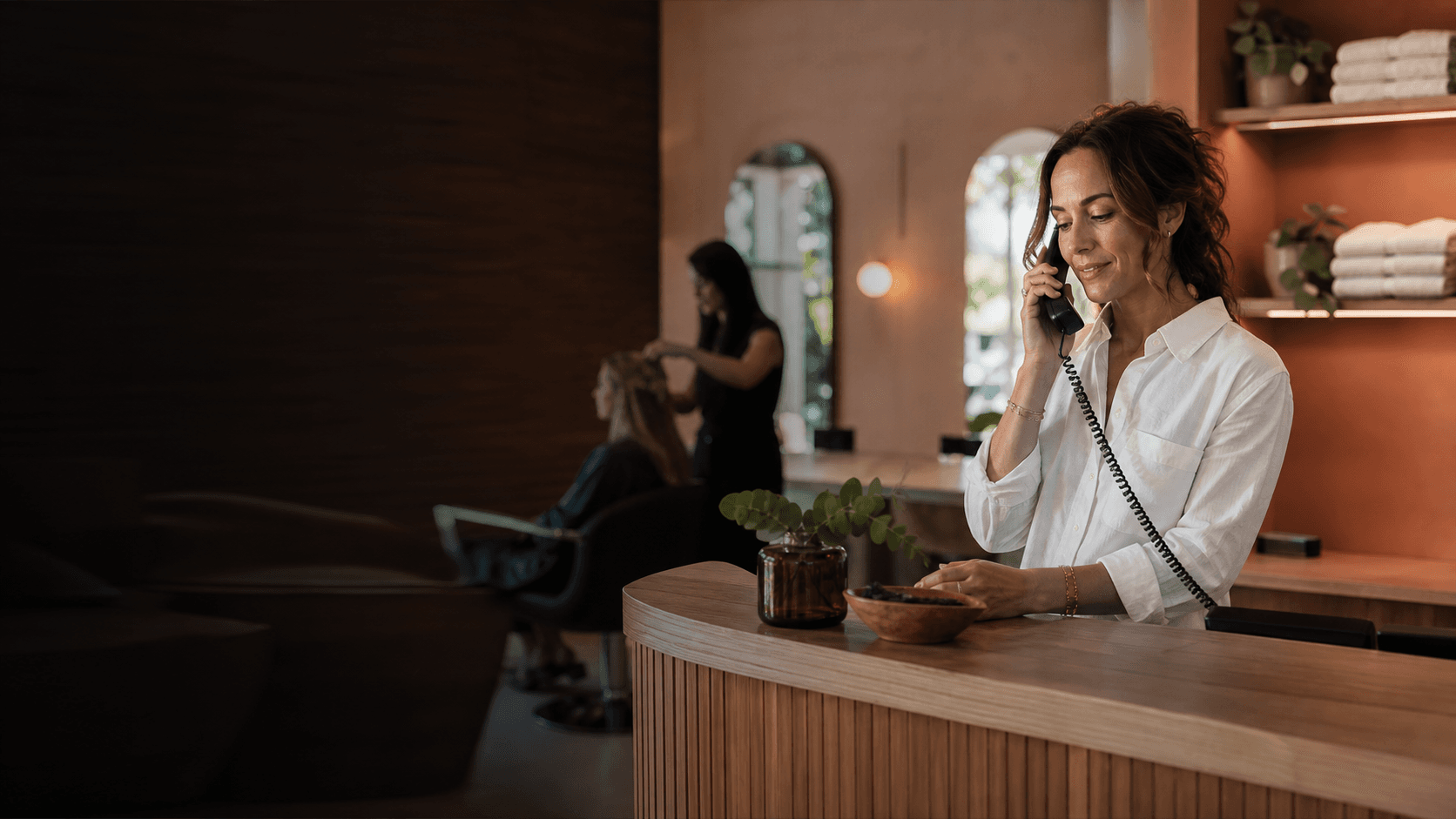 Salon owner handling the front desk during a busy appointment